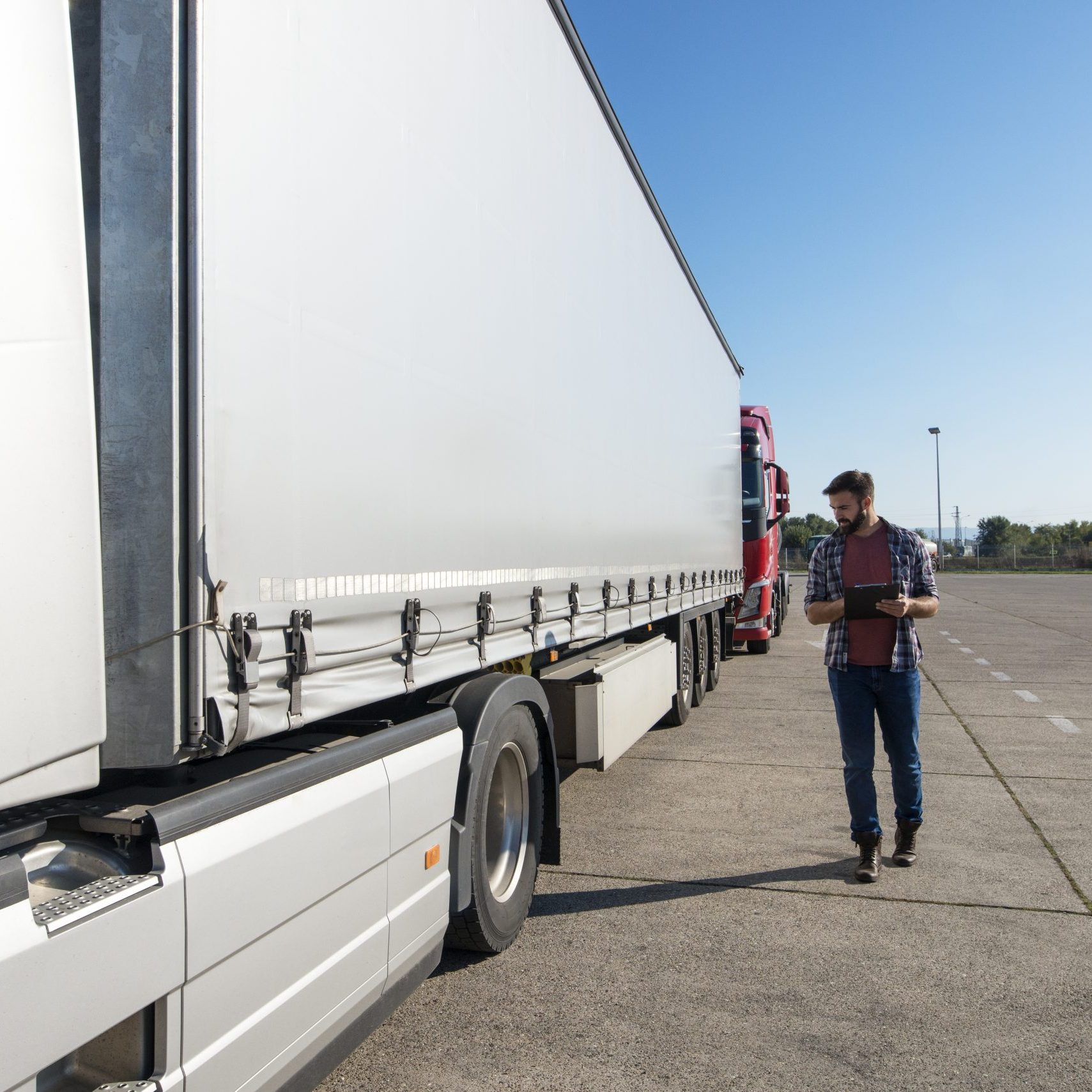 Truck driver inspecting vehicle, trailer and tires before driving.